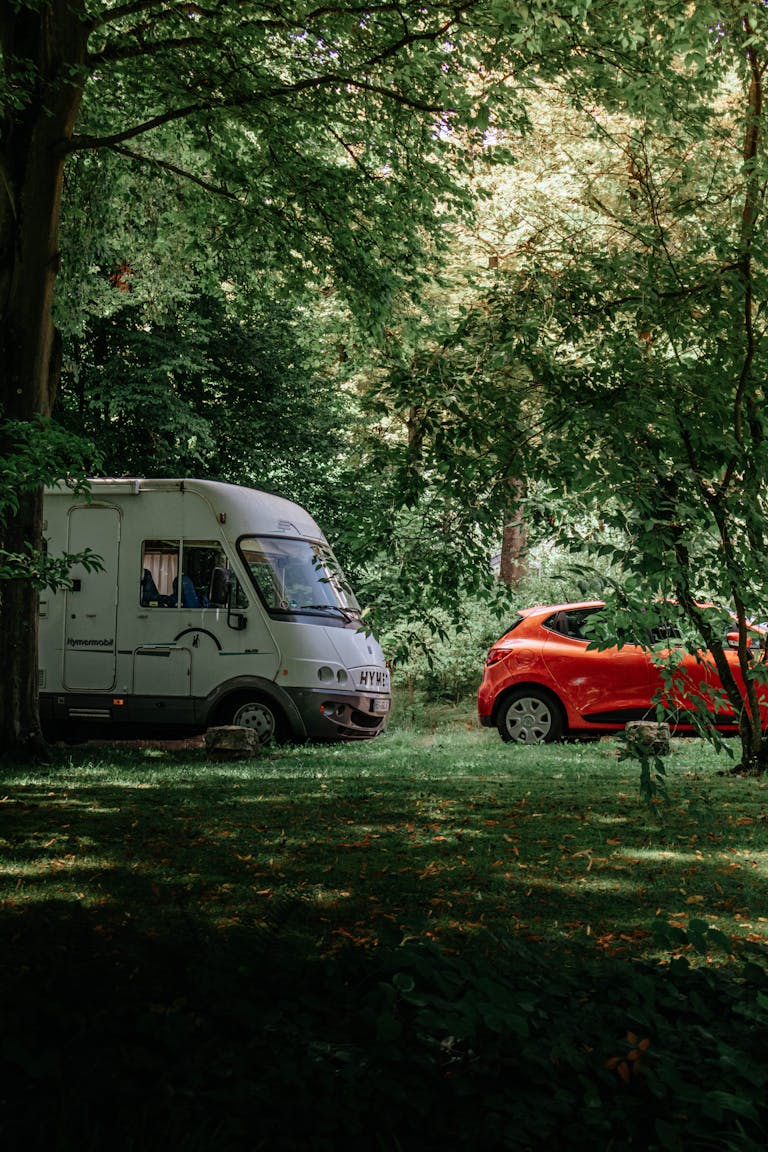 A tranquil campsite featuring a camper and a car parked in a lush green forest during summer in Russia