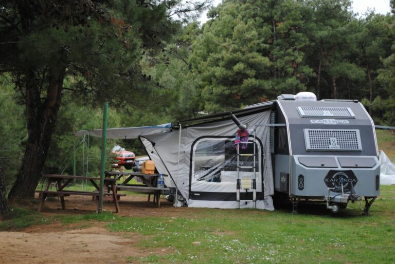 RV at a campsite in a Russian forest with wooden tables