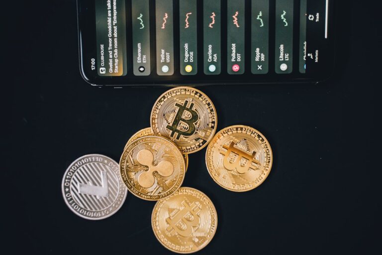 Smartphone with cryptocurrency market data and physical coins on a black surface, representing the method of bringing money to Russia in crypto
