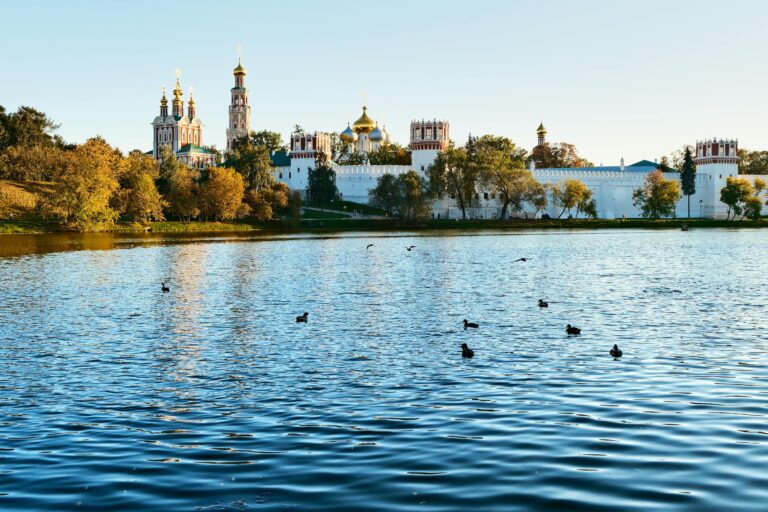 Serene view of Novodevichy Convent reflected in a tranquil lake under a clear sky