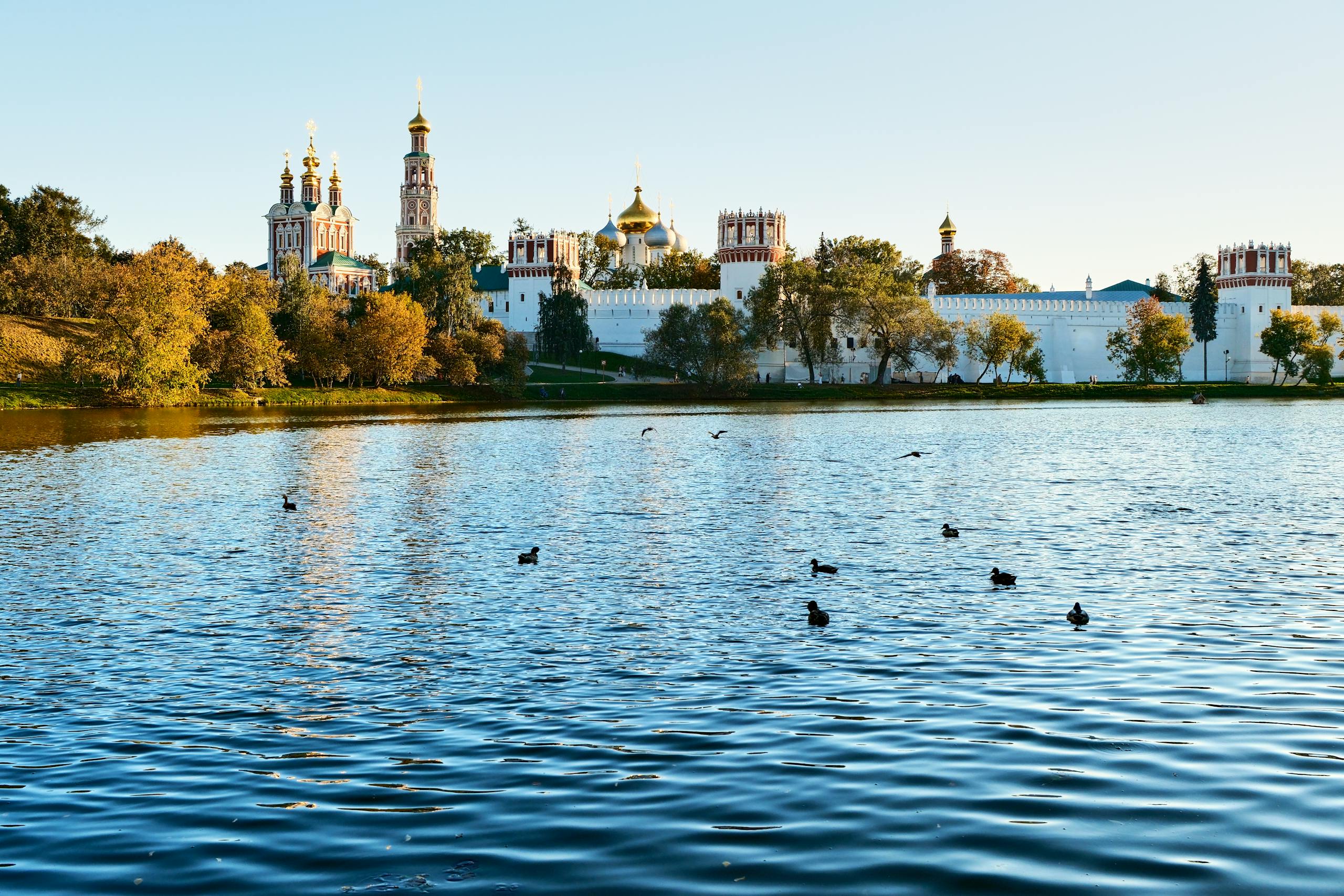 Serene view of Novodevichy Convent reflected in a tranquil lake under a clear sky