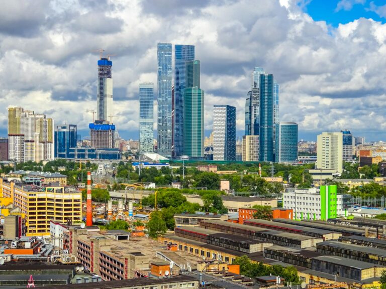 Skyline of Moscow with modern skyscrapers and industrial district under cloudy sky
