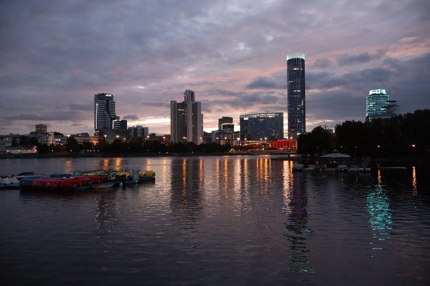 Yekaterinburg skyline reflected in the city pond at dusk with pedal boats moored in the foreground