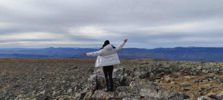 Traveller with open arms on the rocky summit of Mount Iremel in the Southern Urals