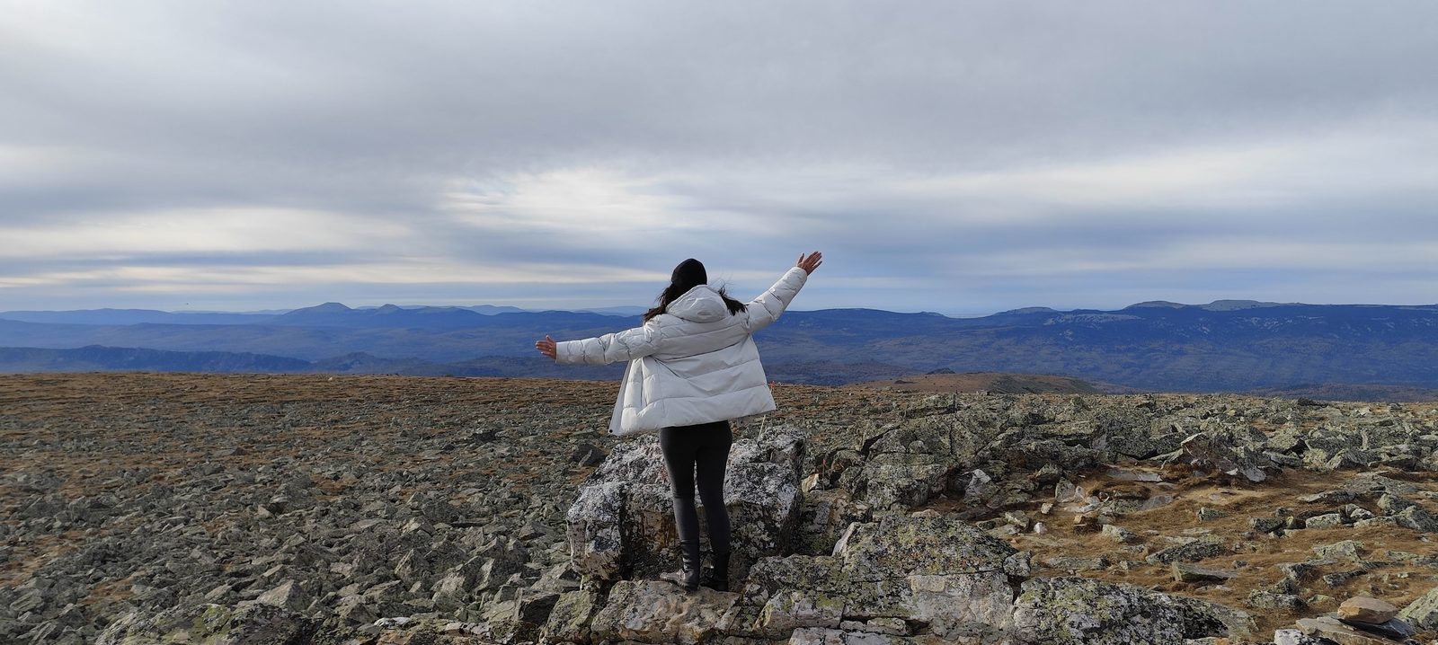 Traveller with open arms on the rocky summit of Mount Iremel in the Southern Urals