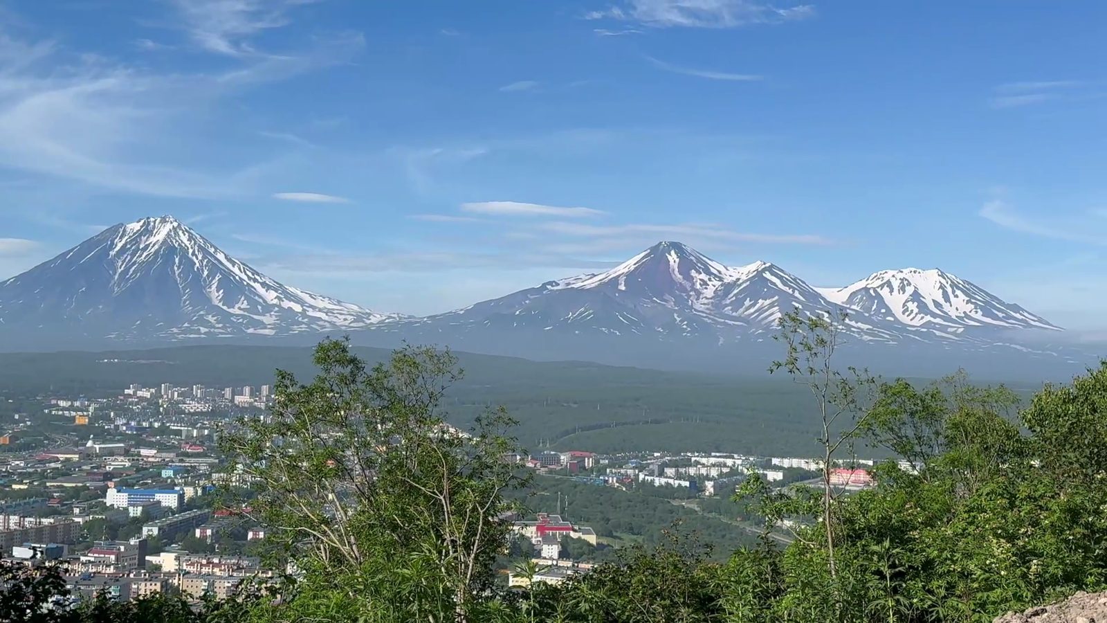 Snow-capped volcanoes rising above the city of Petropavlovsk-Kamchatsky on a clear day