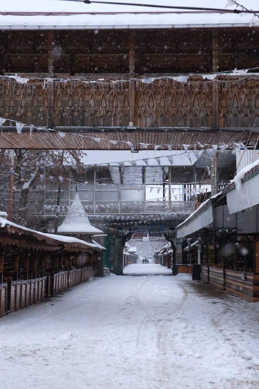 A snow-covered alley between wooden stalls at the Izmailovo market in Moscow