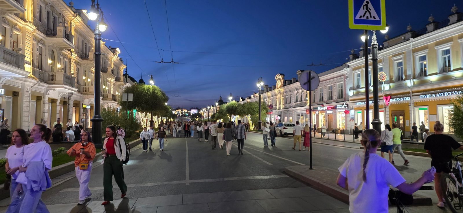 A busy, lit-up pedestrian street with historic buildings on a September evening