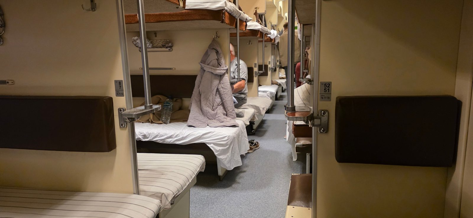 Inside an open-plan third-class platzkart carriage on a Russian night train, with made-up berths