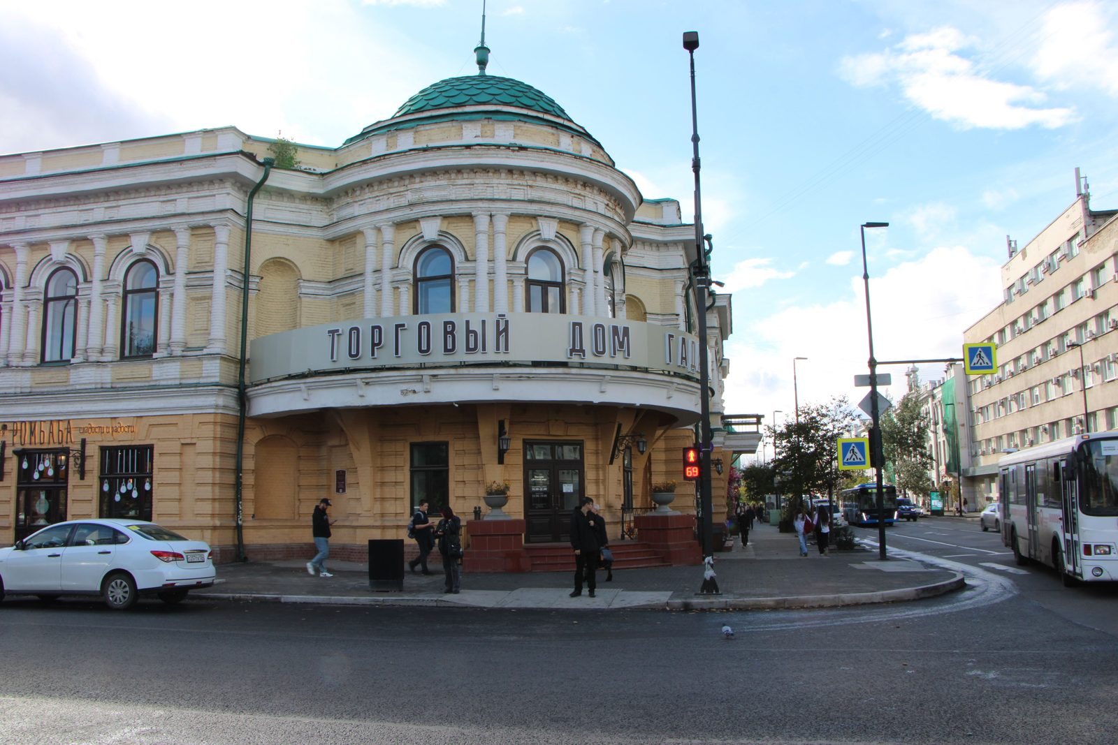 A historic yellow Trading House building with a green dome on a street corner in Siberia