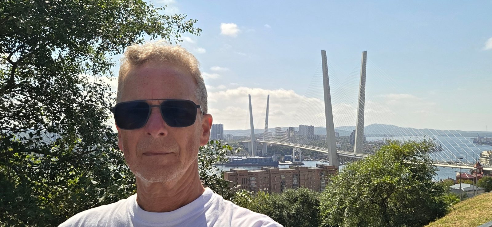 Michael in sunglasses with the Golden Bridge and the bay of Vladivostok behind him